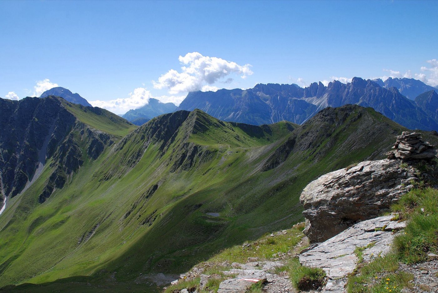 A hiking trail winding along a green alpine ridge