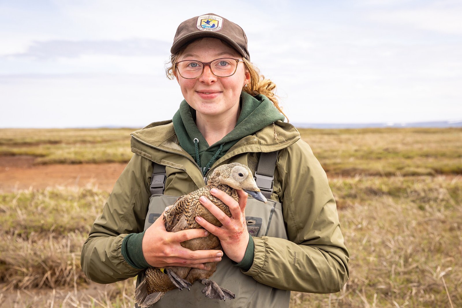 A wildlife biologist holding a bird in the field