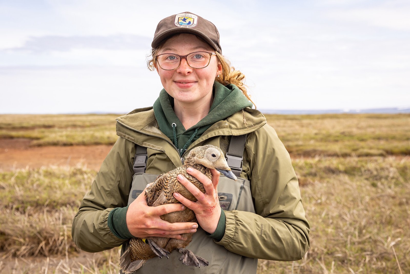 A wildlife biologist holding a bird in the field